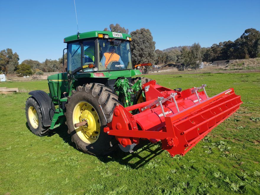 Side view of a yellow disc tiller in a field.