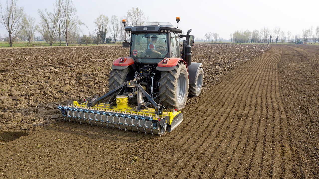 A tractor is plowing a field with a plow attached to it.