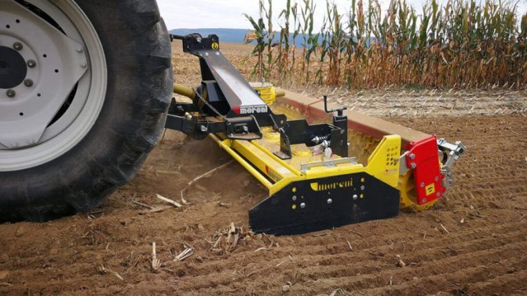 A tractor is plowing a field with a yellow and black machine.