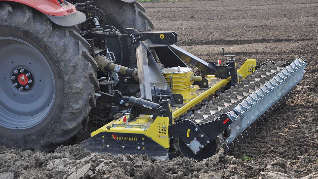 A tractor is plowing a field with a plow attached to it.