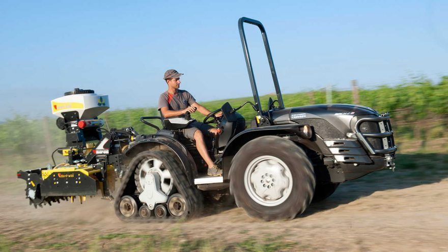 A man is driving a tractor on a dirt road.