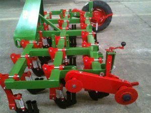 A green and red tractor is parked on the side of the road.
