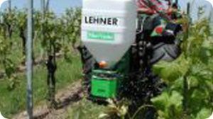 A lehner container is attached to a tractor in a vineyard