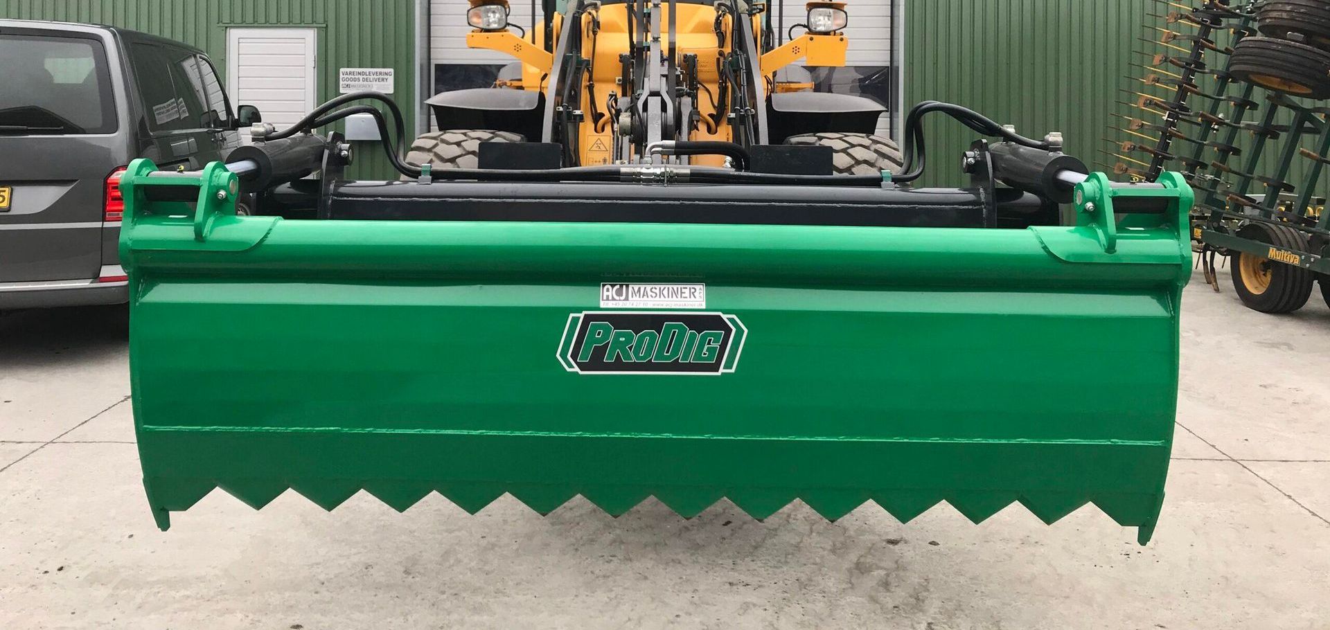 A green tractor is parked in front of a building.