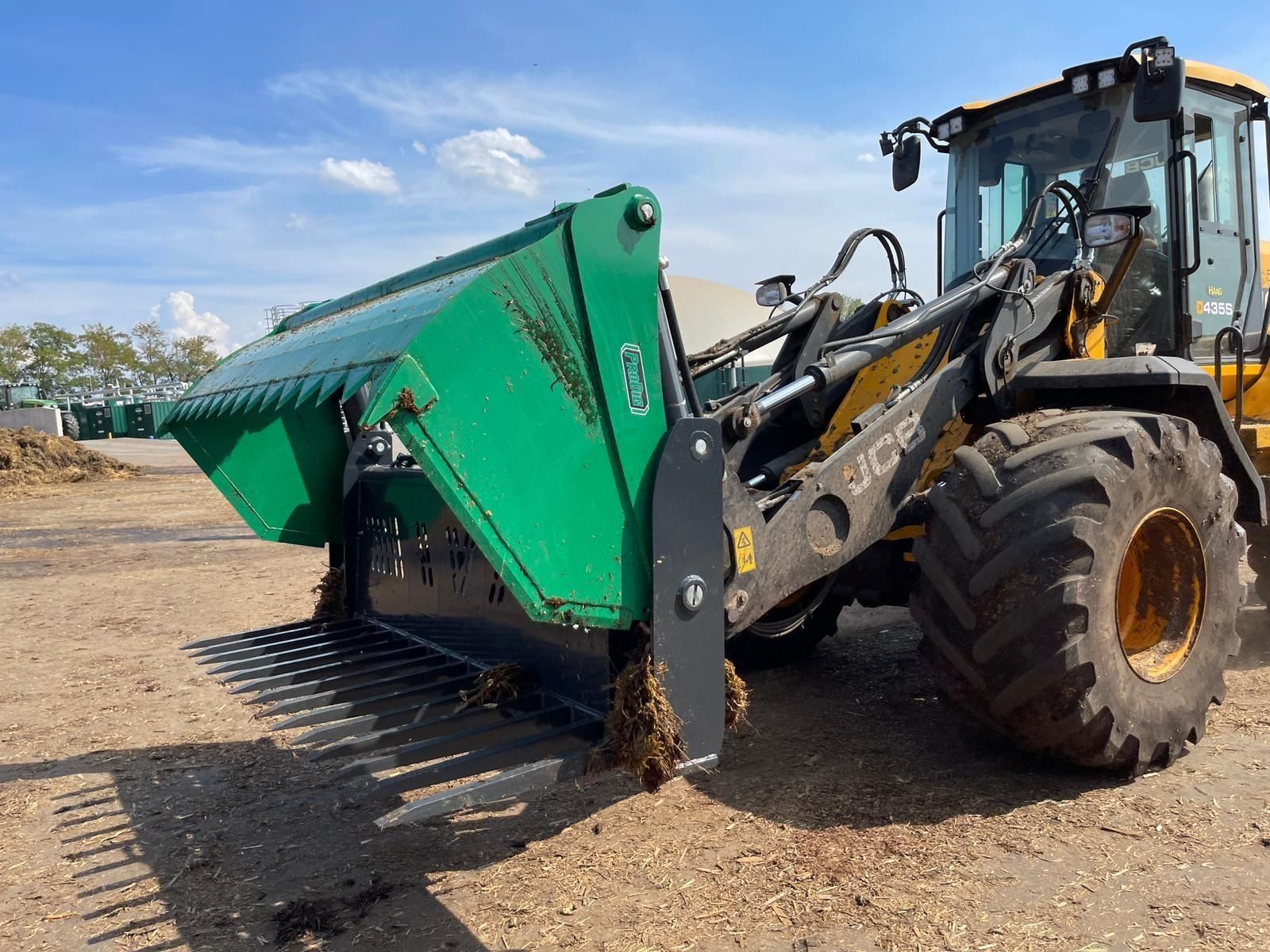 A yellow and green tractor is parked in a dirt field.