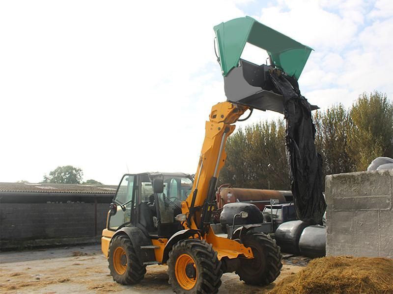 A yellow tractor is loading hay into a bucket.