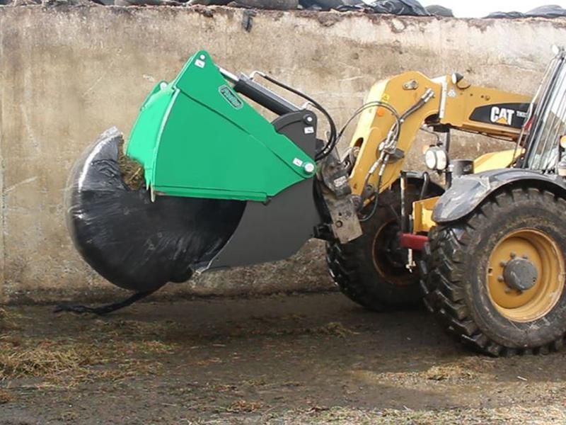 A yellow cat tractor with a green bucket attached to it