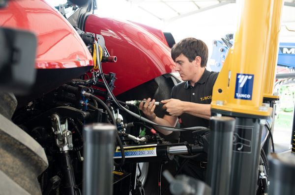 A man is working on a red tractor in a garage.