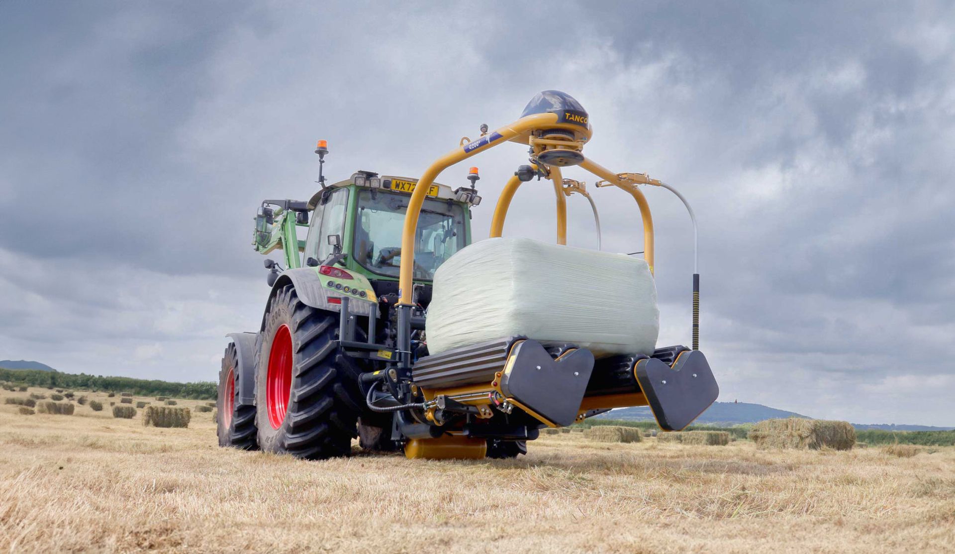 A tractor is wrapping a bale of hay in a field.
