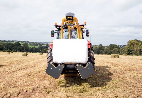 A tractor is wrapping hay bales in a field.