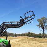 A green tractor is driving through a dry grass field.