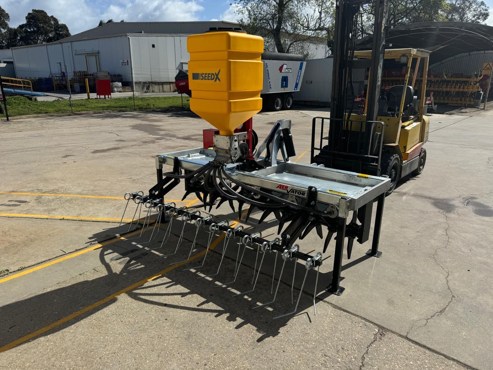 A yellow forklift is parked next to a aerator