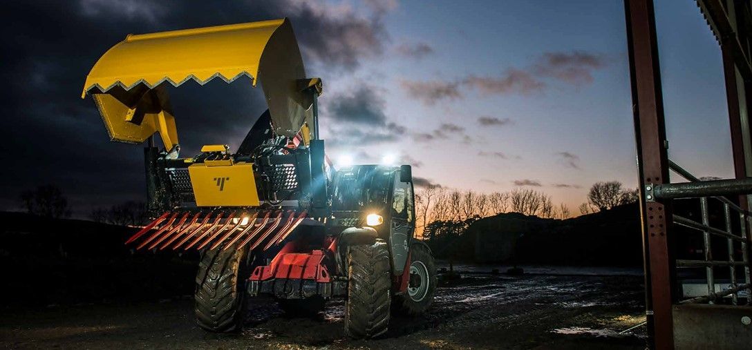 A yellow tractor is parked in a field at night.