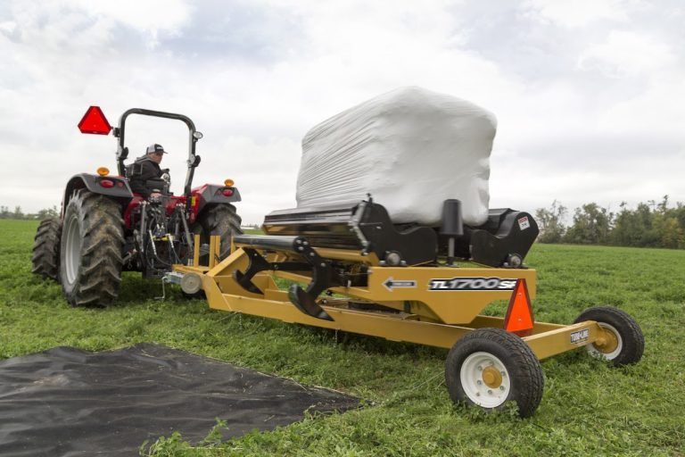 A tractor is wrapping a bale of hay in a field.