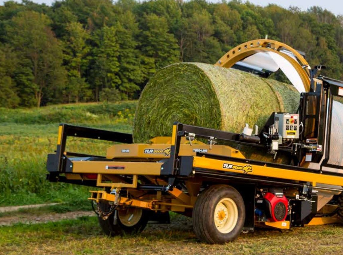 A machine is wrapping a bale of hay in a field.