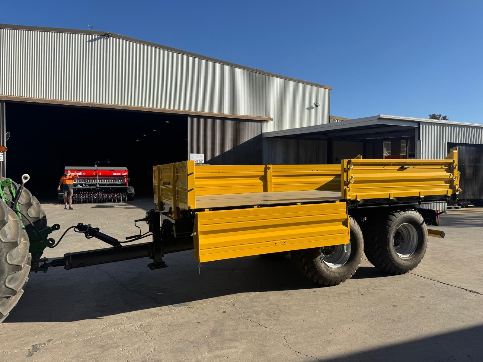 A yellow trailer is parked in a grassy field.