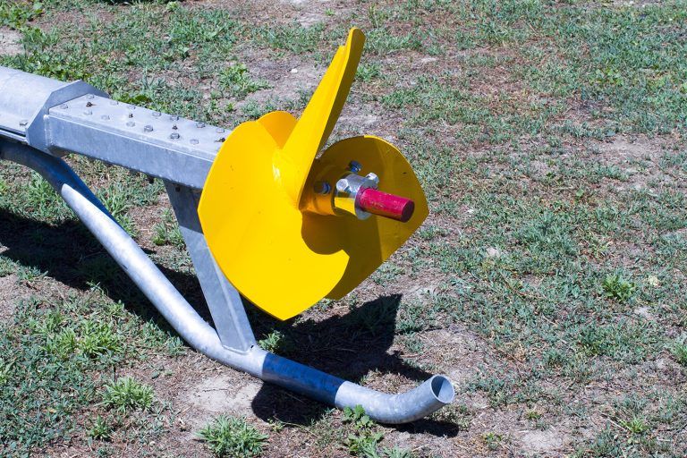 A yellow object is sitting on the ground in the grass.