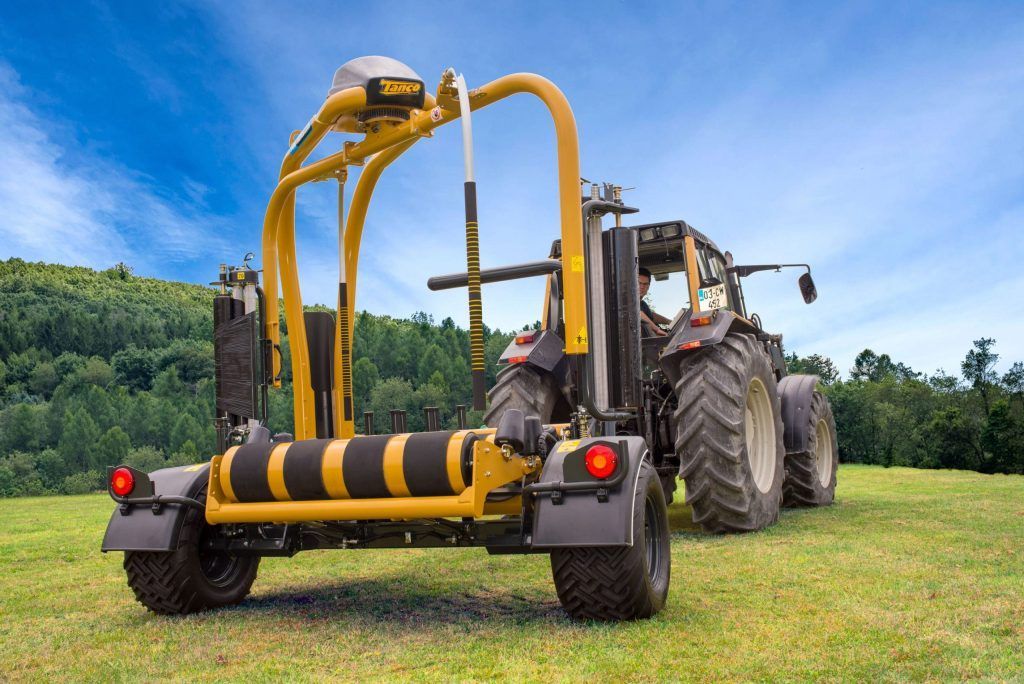 A yellow and black tractor is parked in a grassy field.
