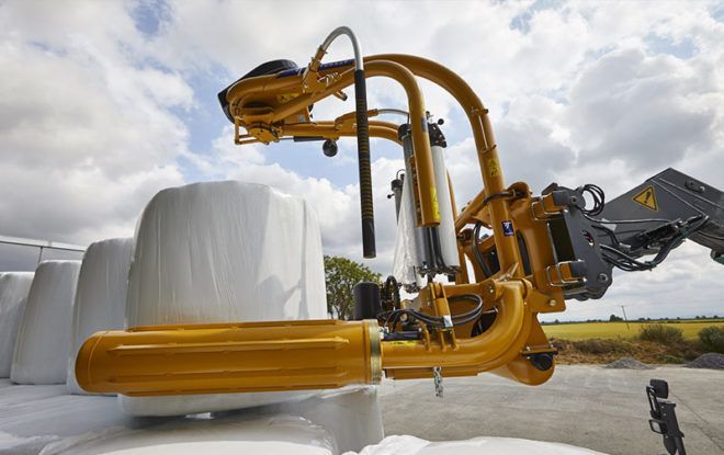 A machine is wrapping a bale of hay in plastic.