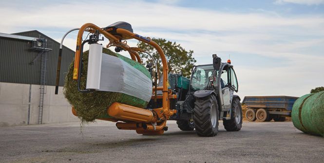 A tractor is wrapping a bale of hay in plastic.