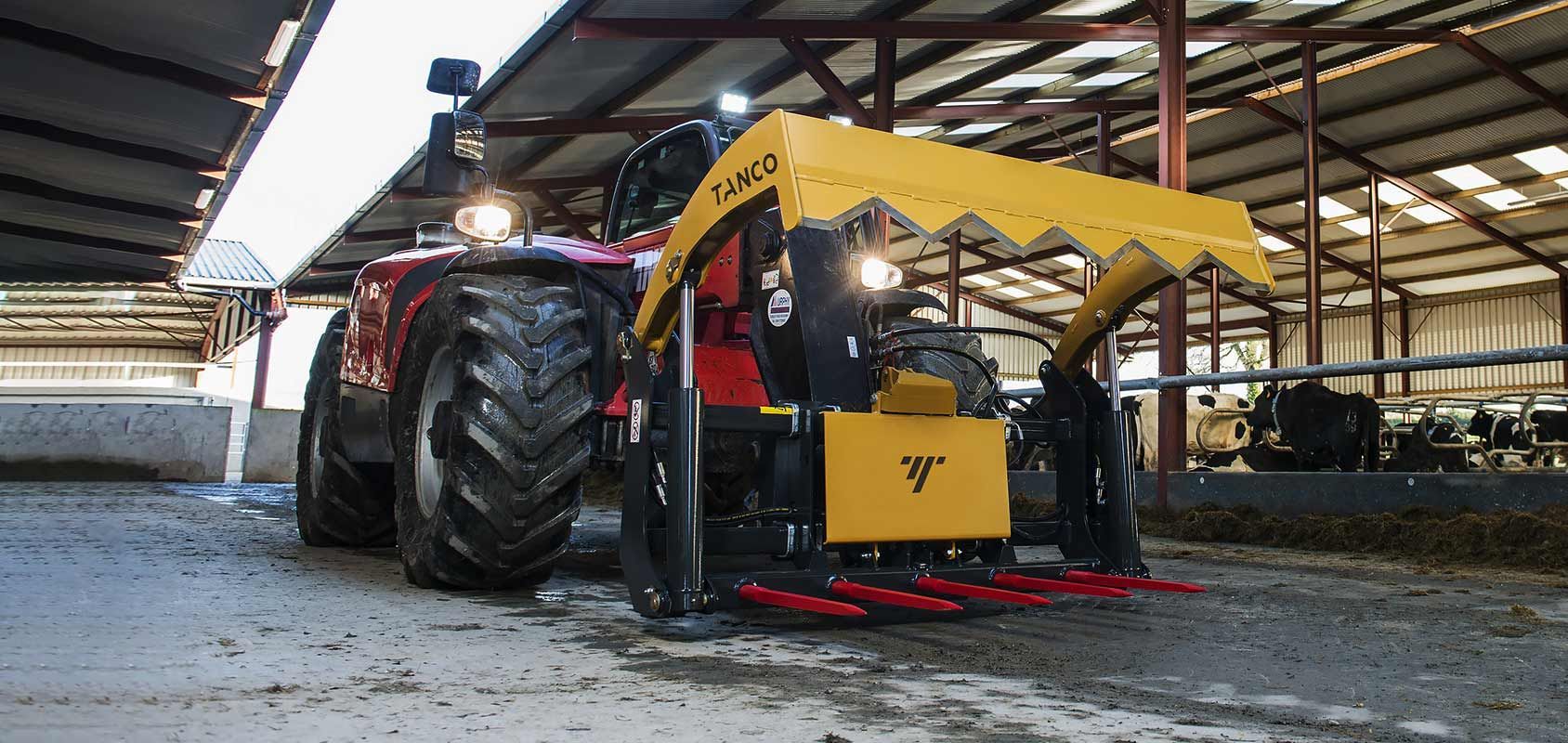 A red and yellow tractor is parked in a barn.