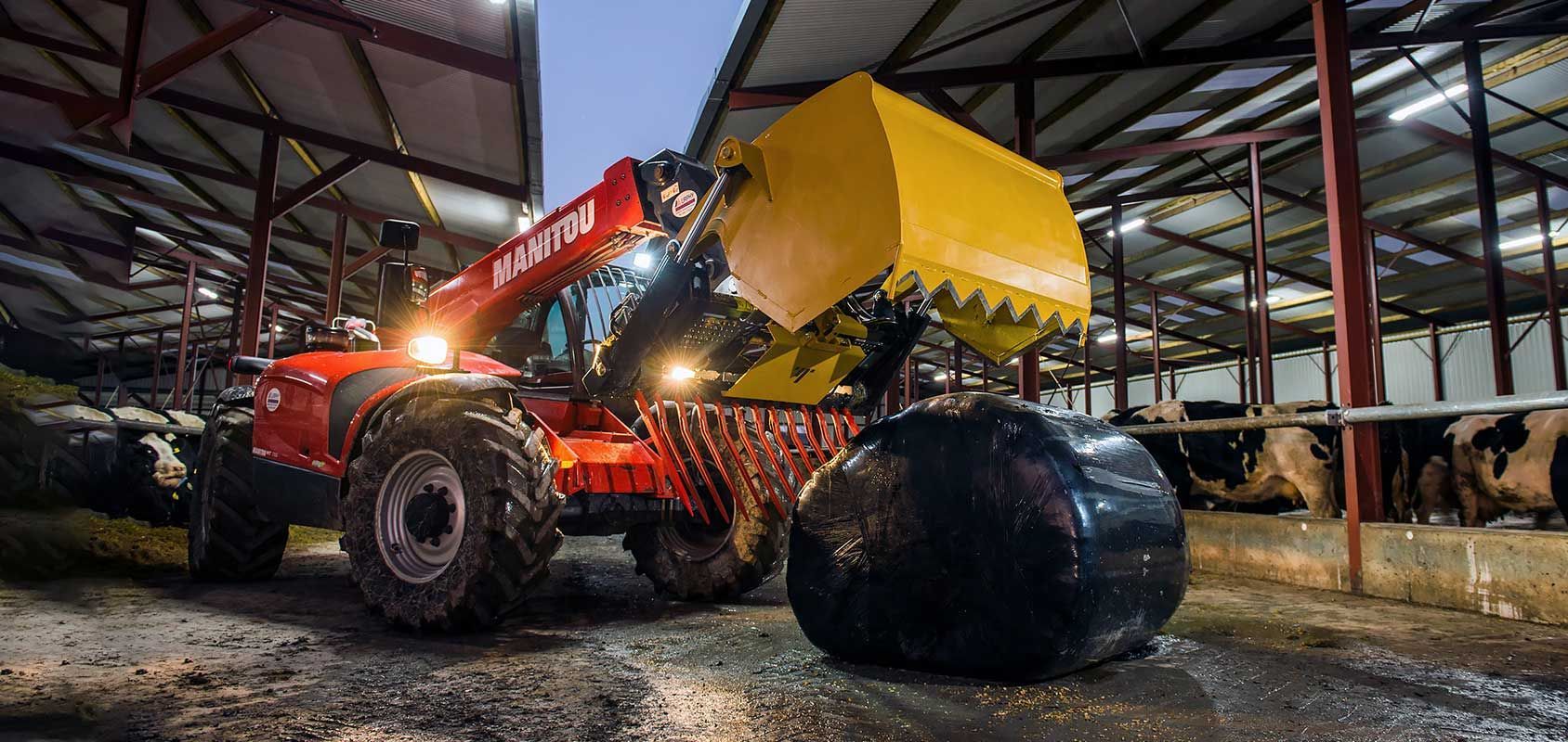 A tractor is loading bales of hay into a barn.