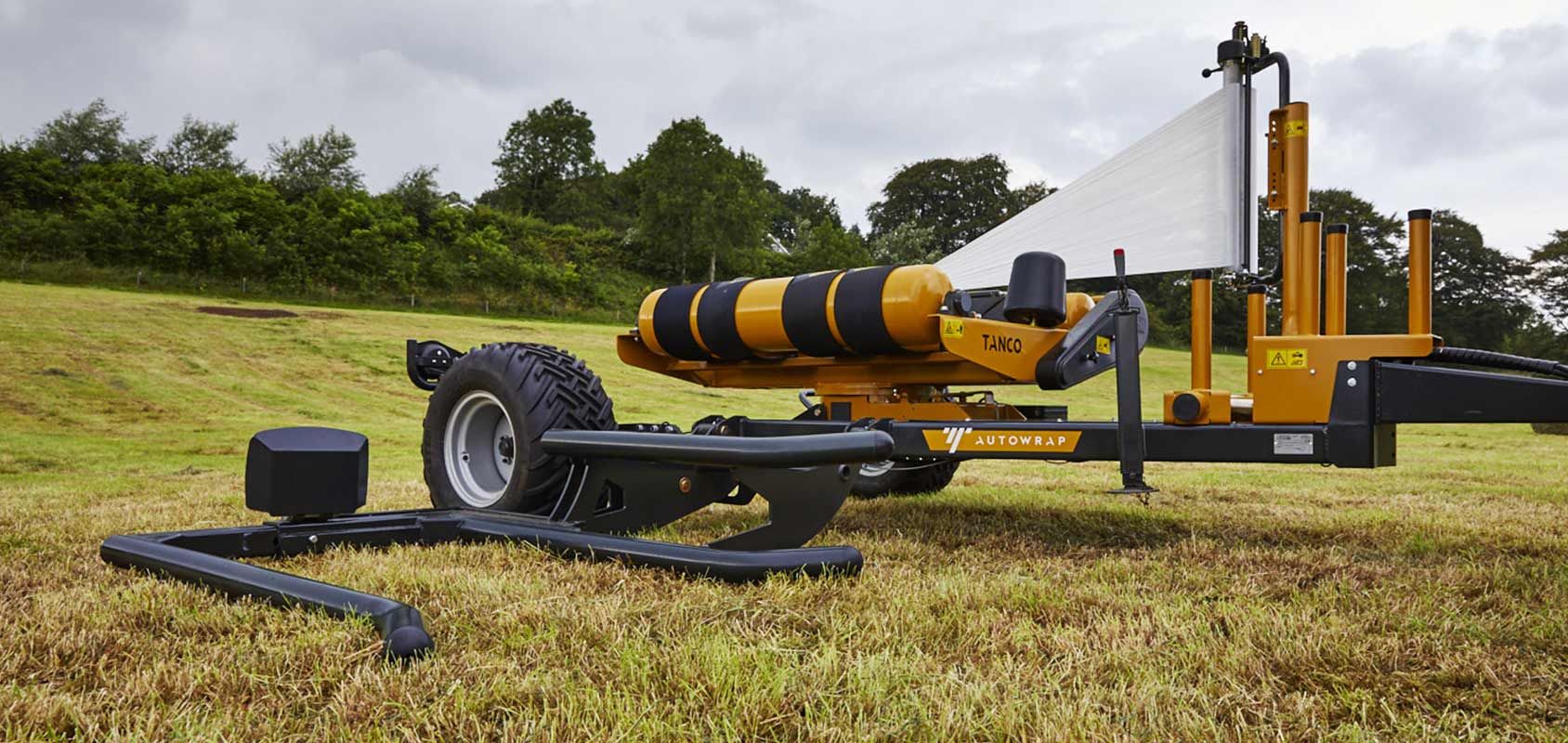 A yellow and black machine is sitting on top of a lush green field.