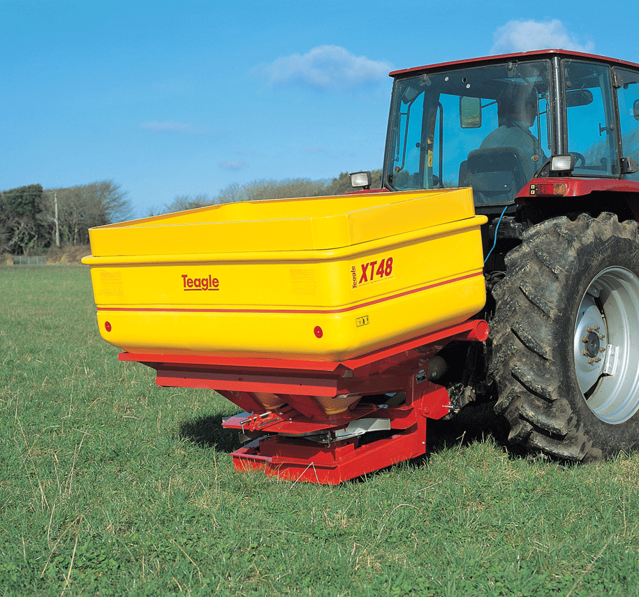 A tractor with a yellow fertiliser spreader that says XT48 on it