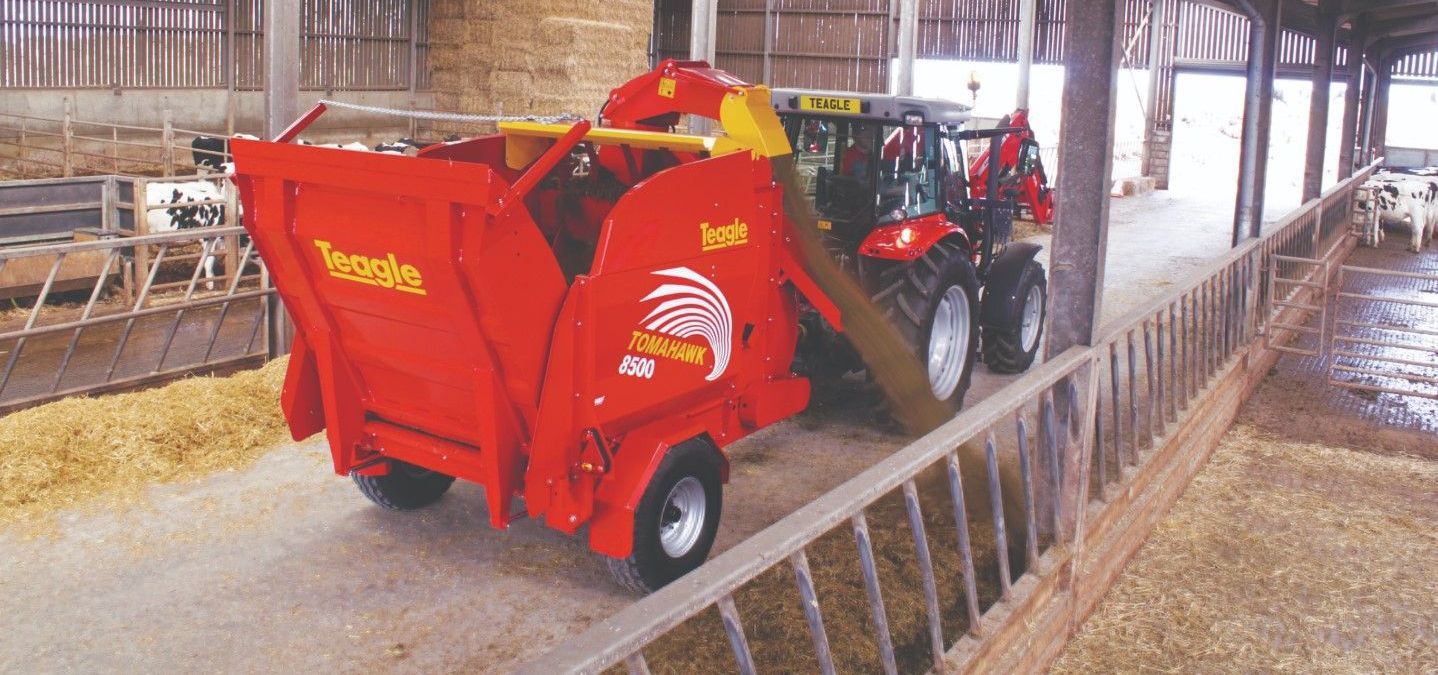 A red and yellow tractor is parked in a barn.