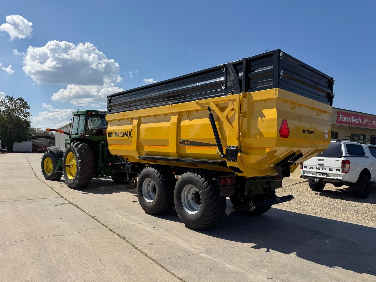 A yellow trailer is attached to a tractor in a dirt field.