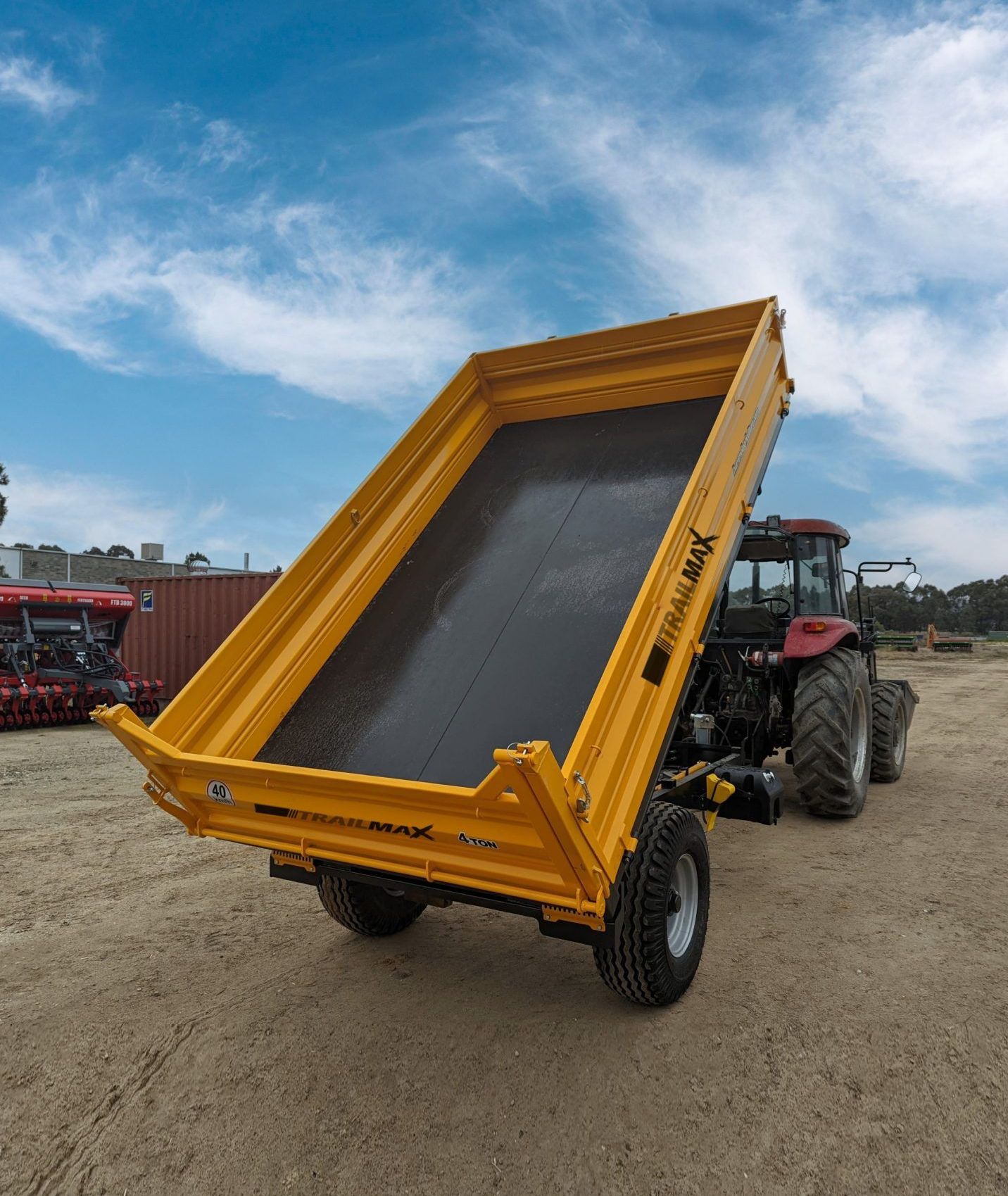 A tractor with a yellow dump trailer attached to it