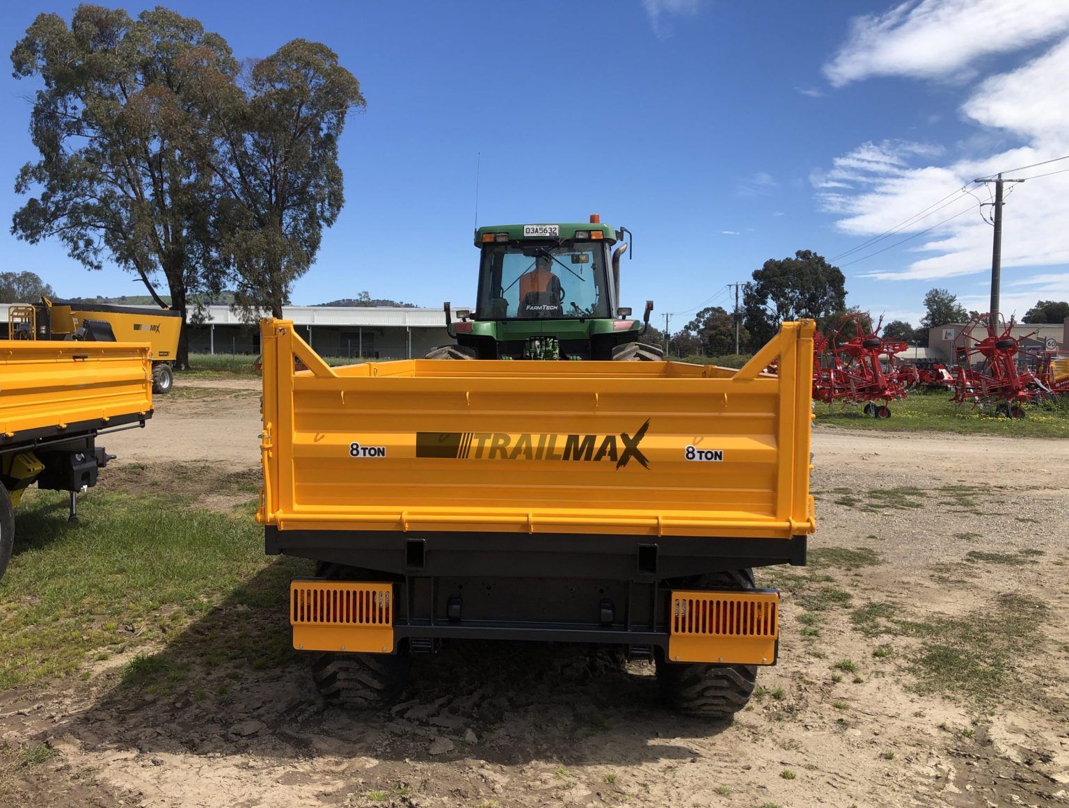 A yellow trailer with a john deere tractor in the background