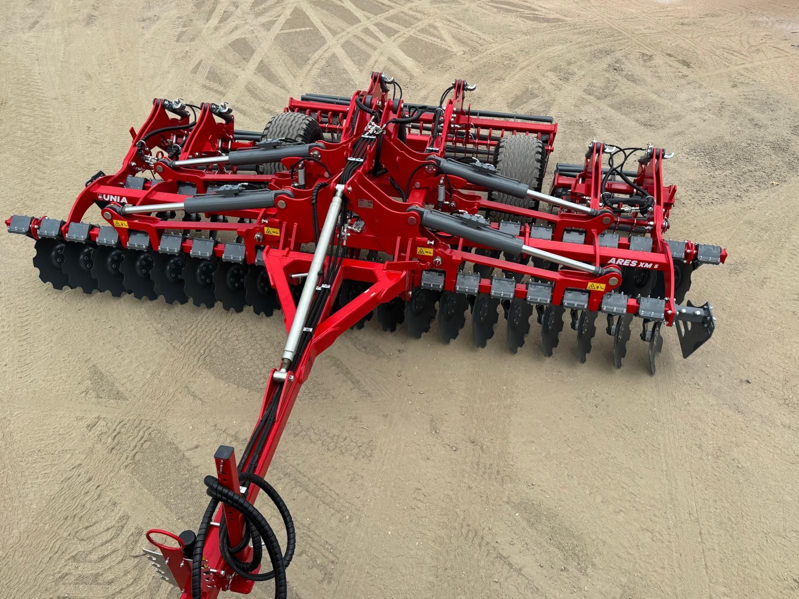 A red and black tractor is plowing a field.