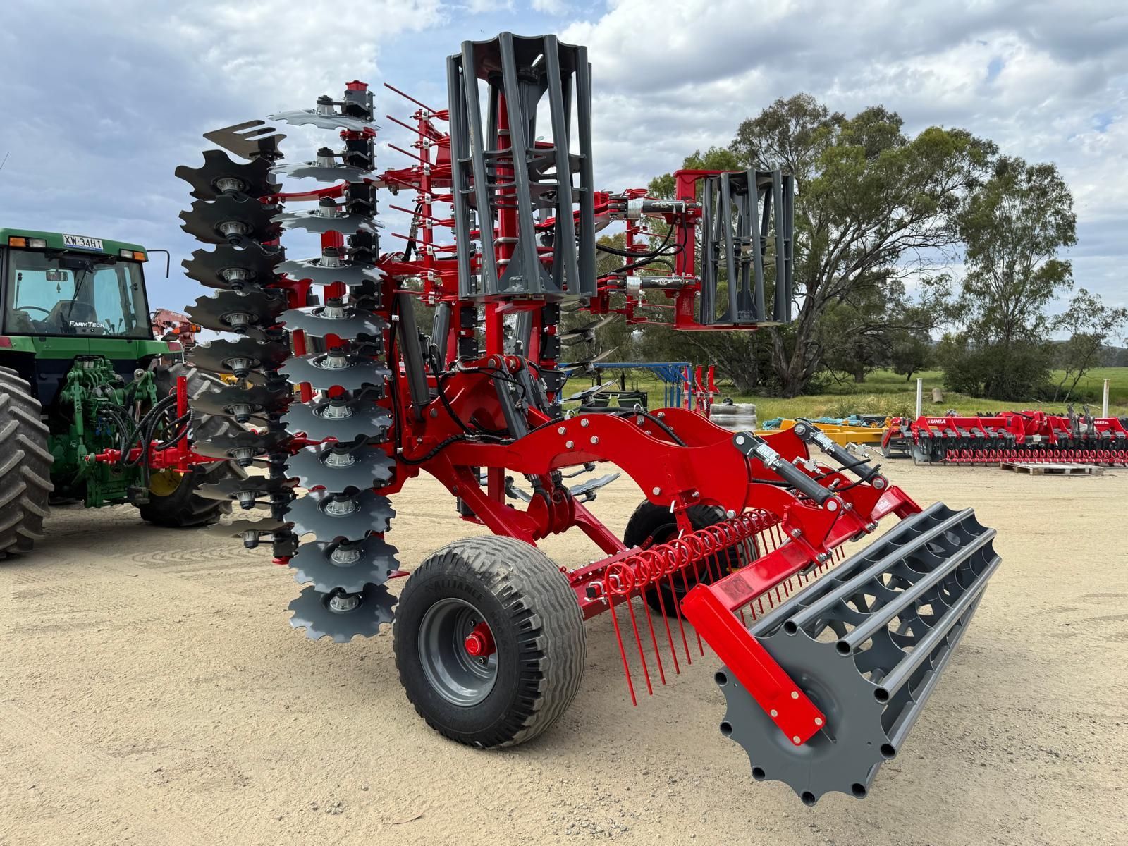 A red and black tractor is plowing a field.