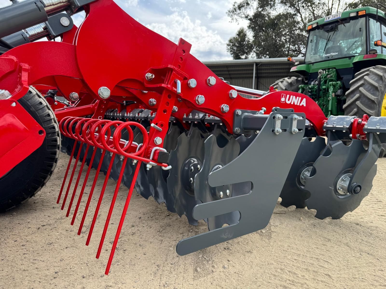 A red and black tractor is plowing a field.