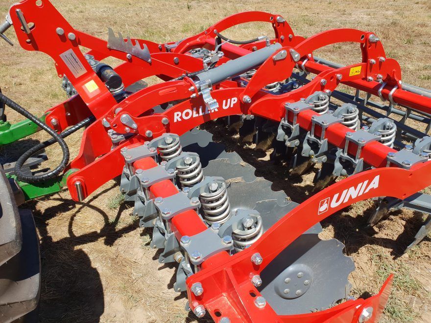 A red and gray disc tiller that says roller up on it