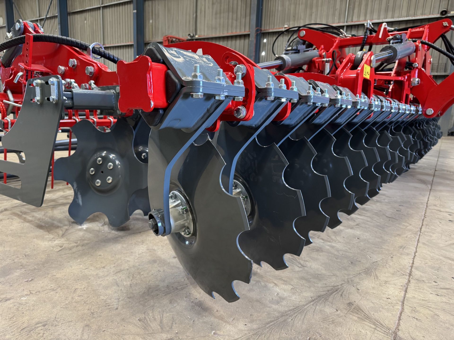 A red and black tractor is sitting in a warehouse.
