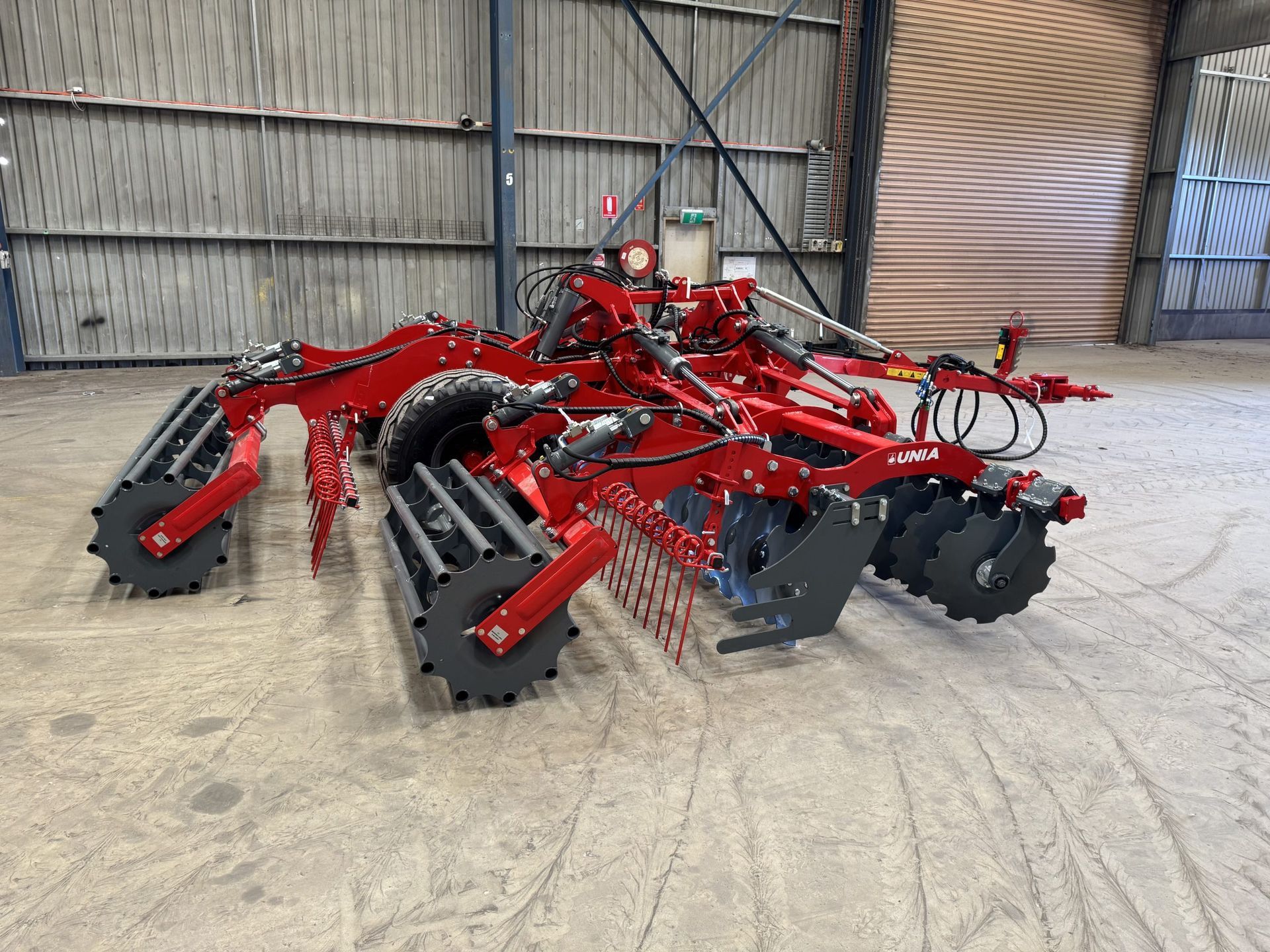A red and black tractor is parked in a warehouse.