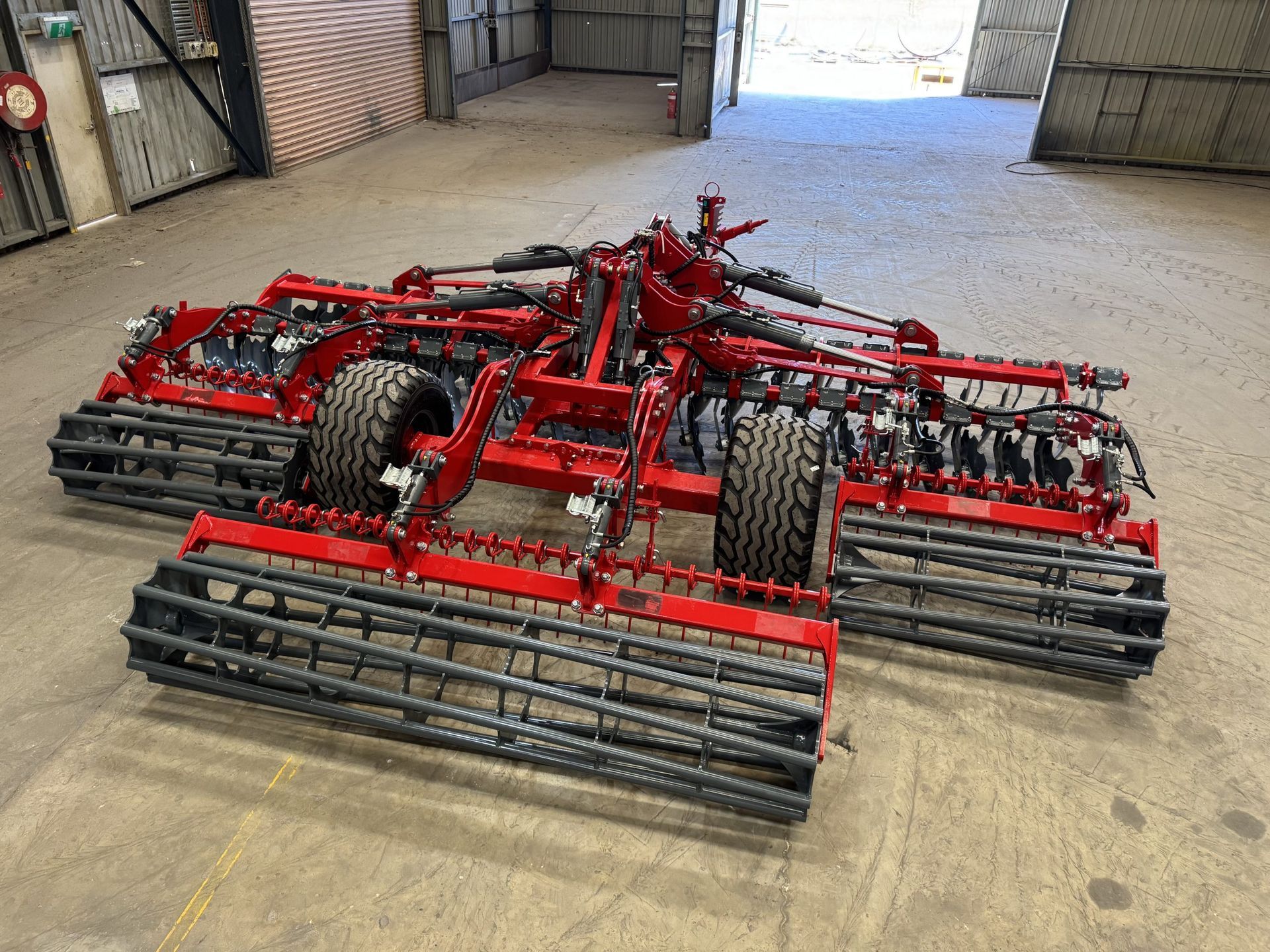 A red and black tractor is parked in a warehouse.