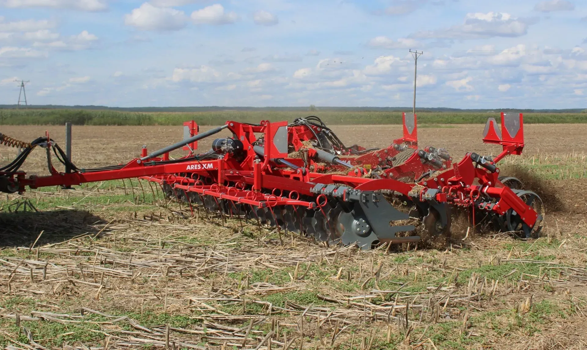 A red and black tractor is plowing a field.