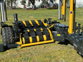 A yellow and black machine is sitting on top of a lush green field.