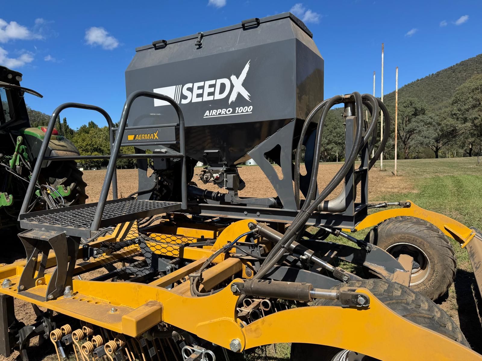A tractor is aerating a field with a machine attached to it.