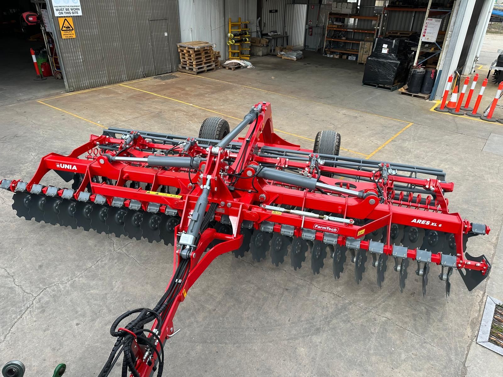 A red and black machine is sitting on top of a dirt field.