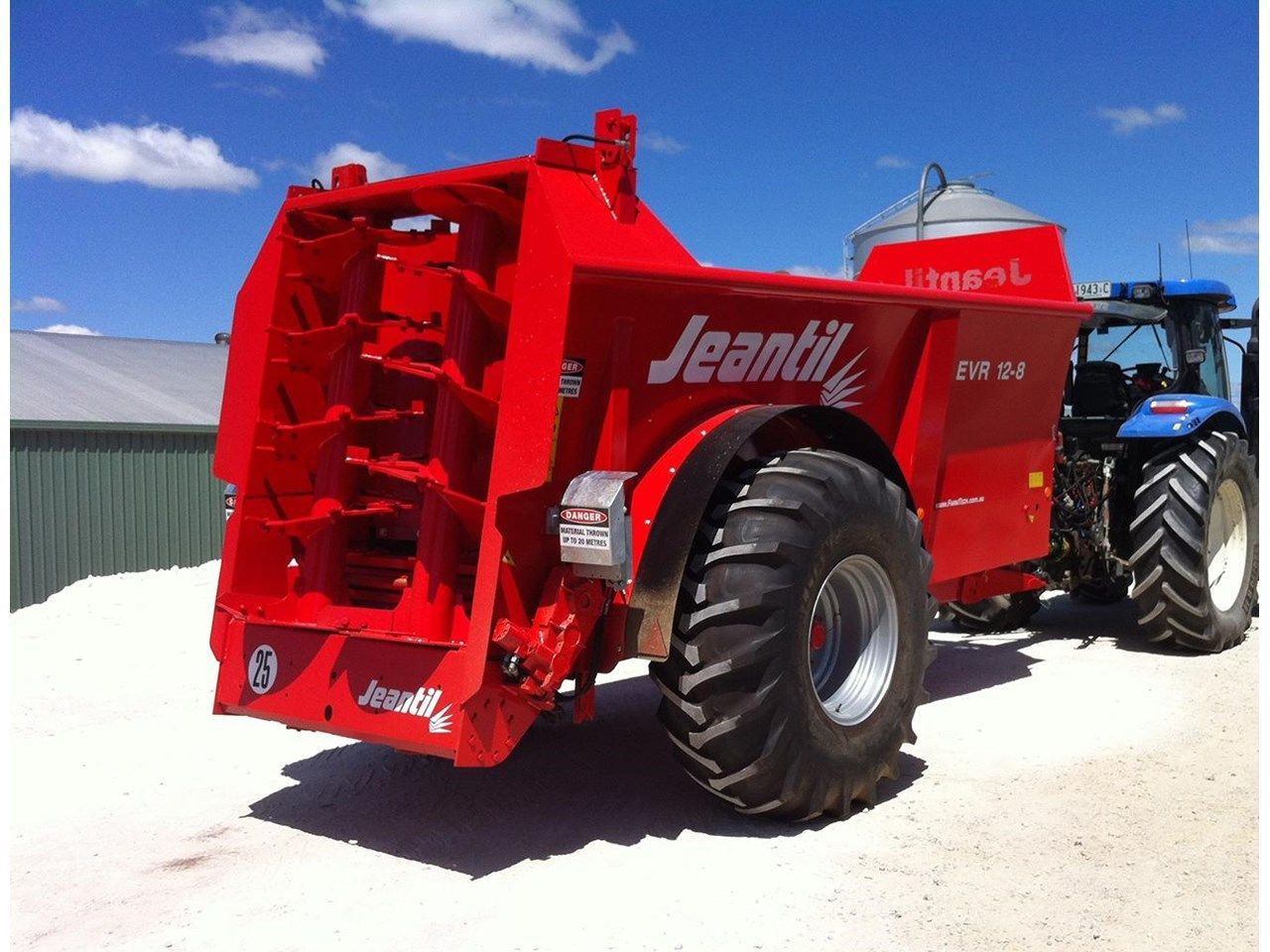 A red jeantil tractor is parked next to a blue tractor