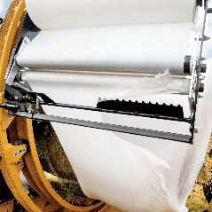 A large roll of paper is being wrapped in plastic