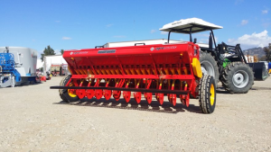 A red and yellow tractor is parked on a dirt road.