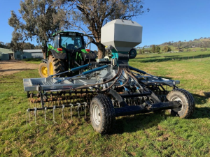 A tractor is plowing a field with a machine attached to it.