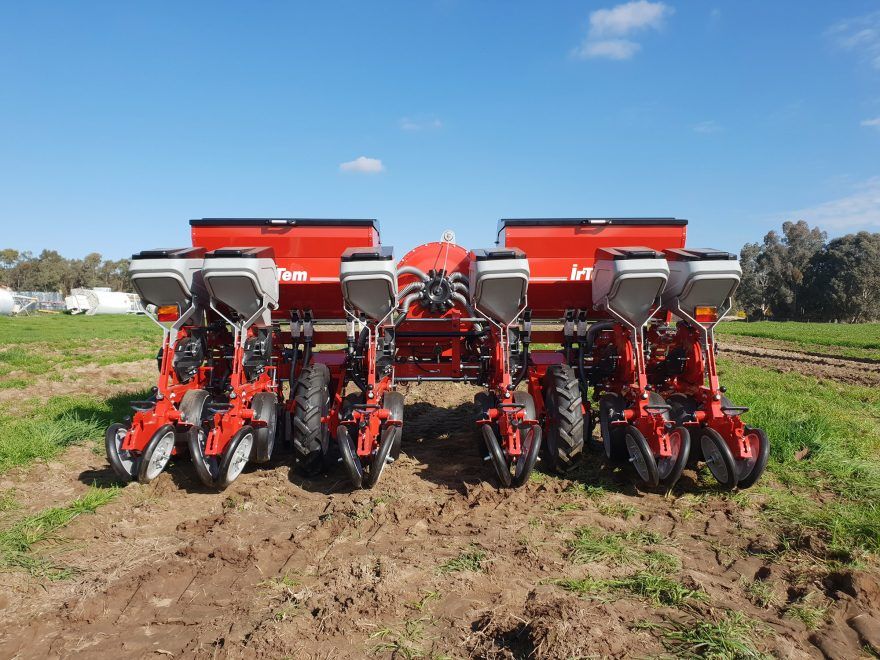 A row of red planters are lined up in a field