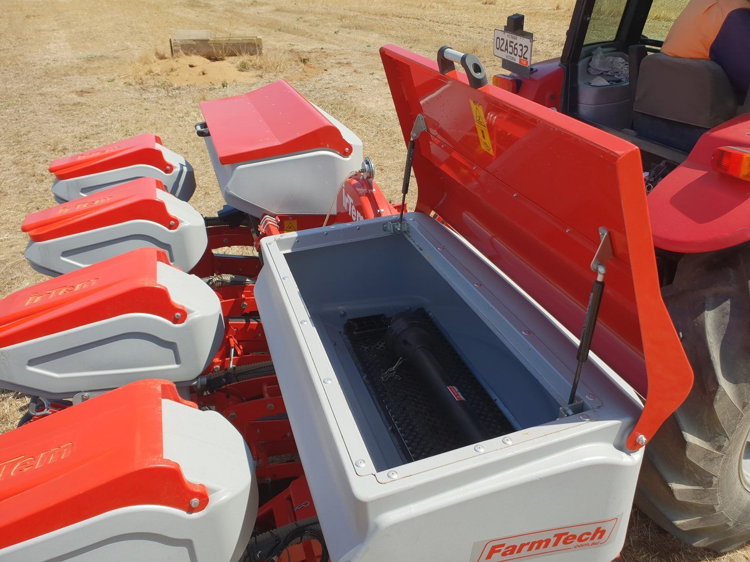 A red and white farm tech planter is parked in a field