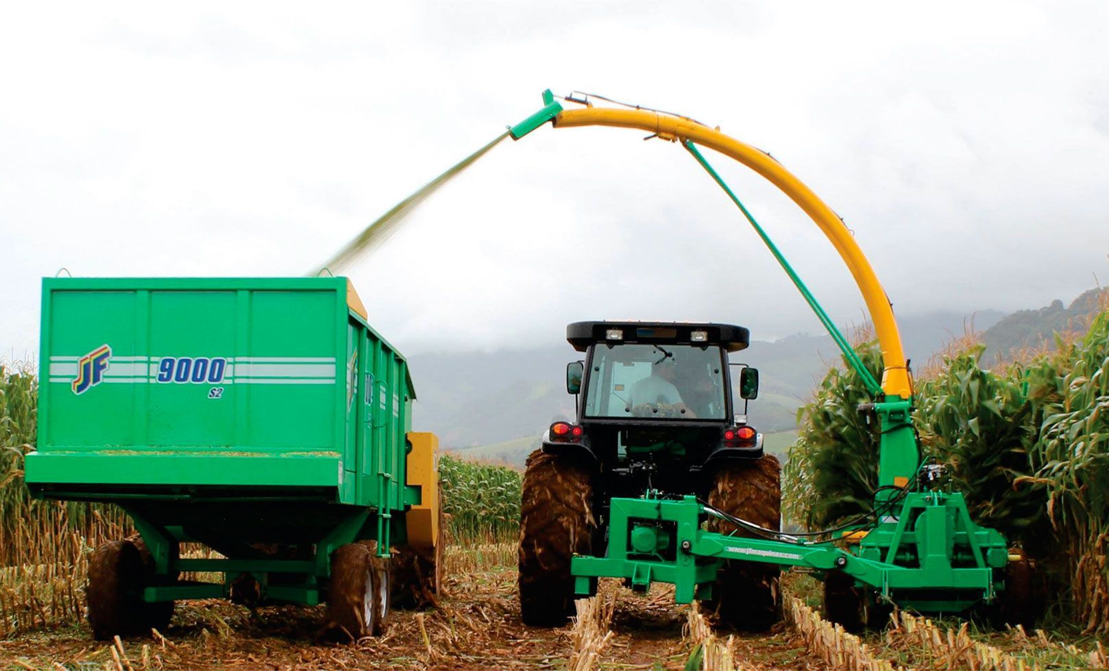 A blue tractor is cutting grass in a field.